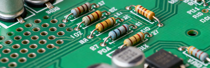 Close-up of PCB with THT components (axial resistors, capacitors) soldered via pre-drilled holes